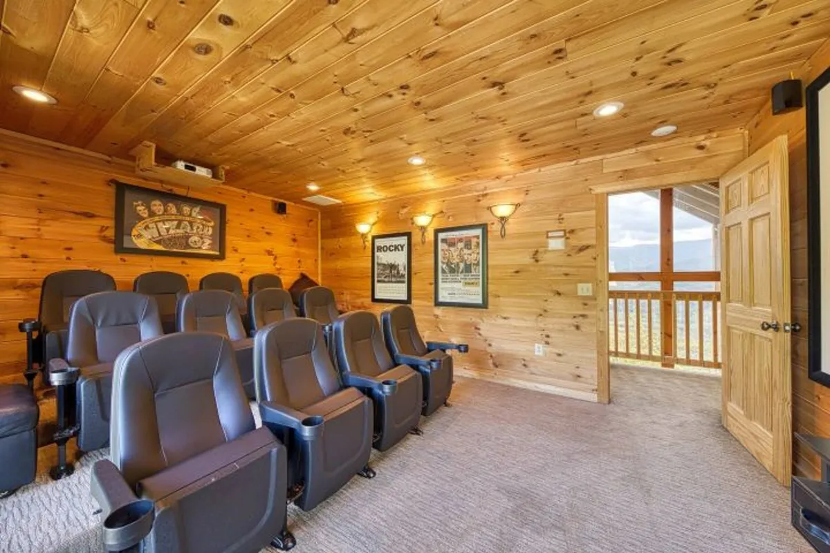 This image captures a stylish home theater with plush, tiered theater seating facing a large screen. Movie posters line the wood-paneled walls, and the room is designed for an immersive viewing experience, suggesting a dedicated space for cinematic enjoyment.