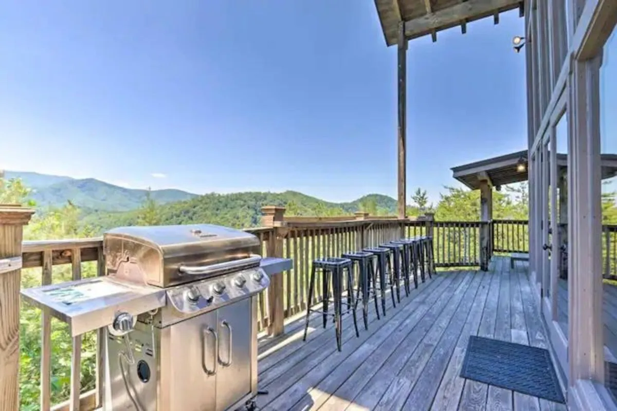 An exterior shot showcasing a spacious outdoor grilling area with bar stools, set against a stunning mountain view. The scene invites guests to gather, barbecue, and enjoy relaxed outdoor dining in a social and scenic setting.