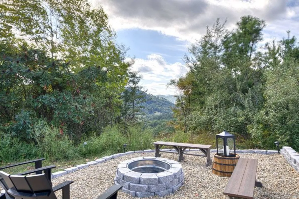 This relaxed exterior setting features a fire pit area with wooden benches, surrounded by greenery and mountain views. The scene is perfect for family gatherings, storytelling, and enjoying s’mores under the stars after a day of adventure.