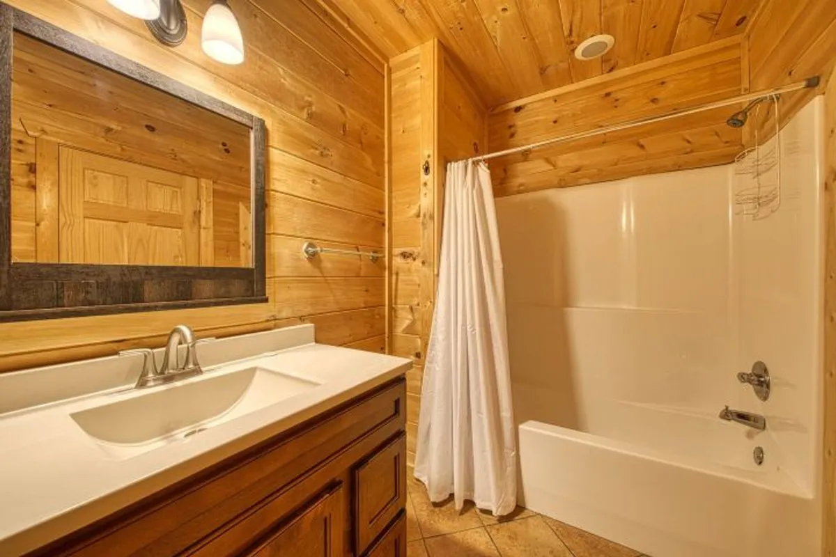 A spa-inspired bathroom featuring a deep soaking bathtub, wooden cabinetry, and a well-lit vanity area. The warm tones and natural textures evoke a sense of relaxation and luxury, perfect for unwinding after a day in the mountains.
